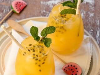 Passion Fruit and Ginger Mojitos in glasses with watermelon swizzle sticks.