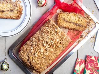 Coffee Cake with Cinnamon & Oats Crumble on a dish, with christmas decorations on wooden background.