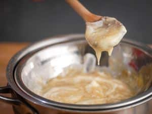 How to Make White Chocolate Ganache - Step 3 image of melted chocolate dripping from wooden spoon - inthekitch.net