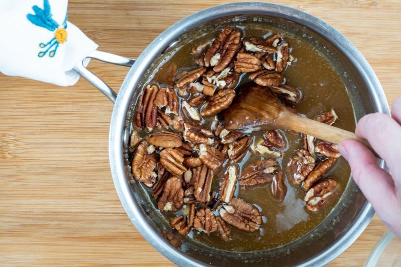 Mixing pralines into pot with sugar mixture.