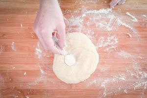Adding salt to dough on floured surface.