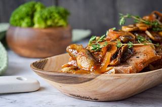 Electric Skillet Pork Chops on a wooden serving platter with a bowl of broccoli on the side.