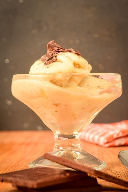Banana ice cream in a glass serving dish with chocolate on top.