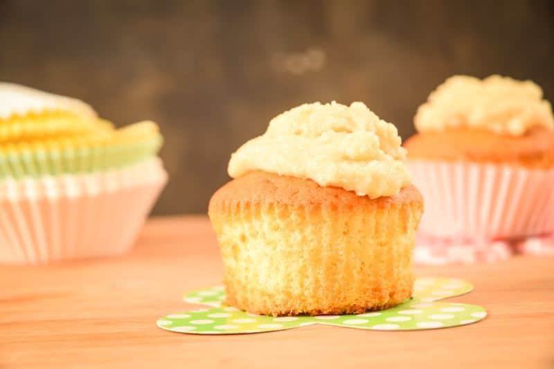 How to Make Buttercream Final 3 Frosted cupcakes on wooden counter.