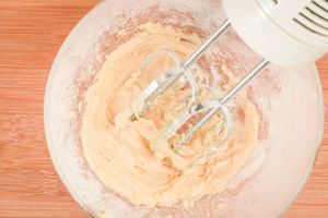 Using a hand mixer to combine vanilla, butter and sugar.
