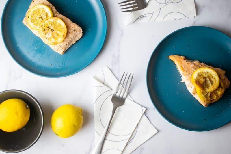 How to Cook Salmon With Skin Step 8-7 Cooked salmon with grilled lemon slices on plates and lemons on the table.
