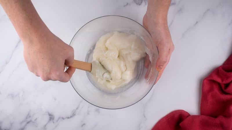 Mochi dough forming in bowl, hands using spatula to mix.