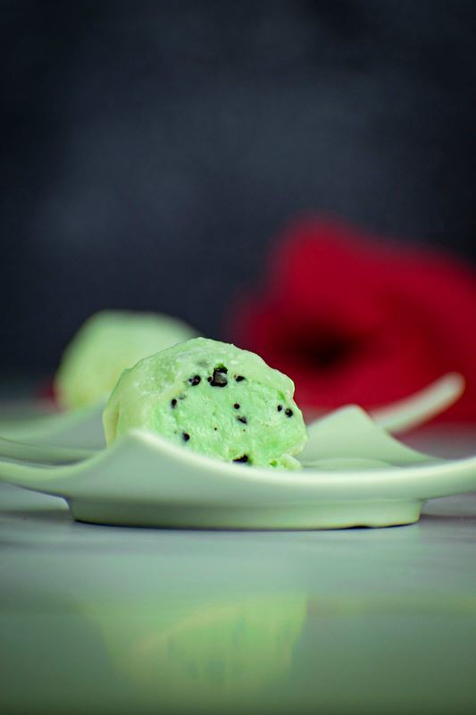 How to Make Mochi Ice Cream Step 9-3 Mint green mochi ice cream that has been cut open, on a mint-colored dish.