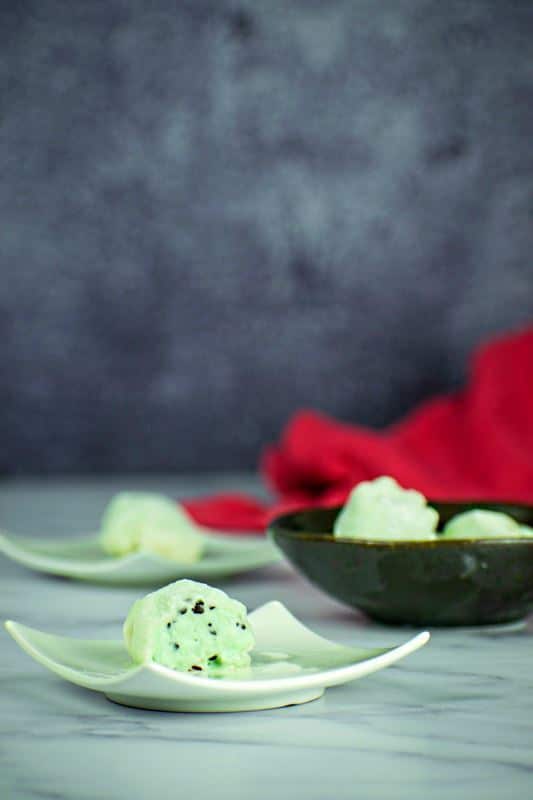 How to Make Mochi Ice Cream Step 9-7 Mint green mochi ice cream that has been cut open, on a mint-colored dish.