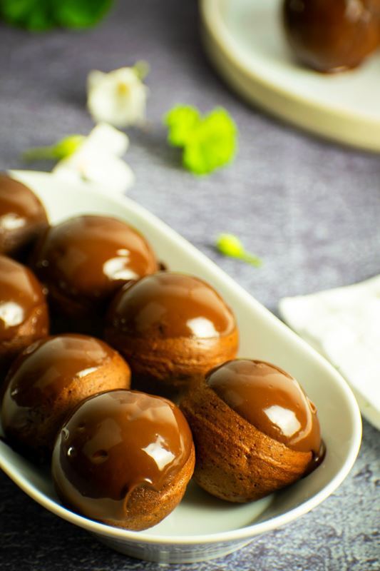 Chocolate covered donut holes on a white serving dish.