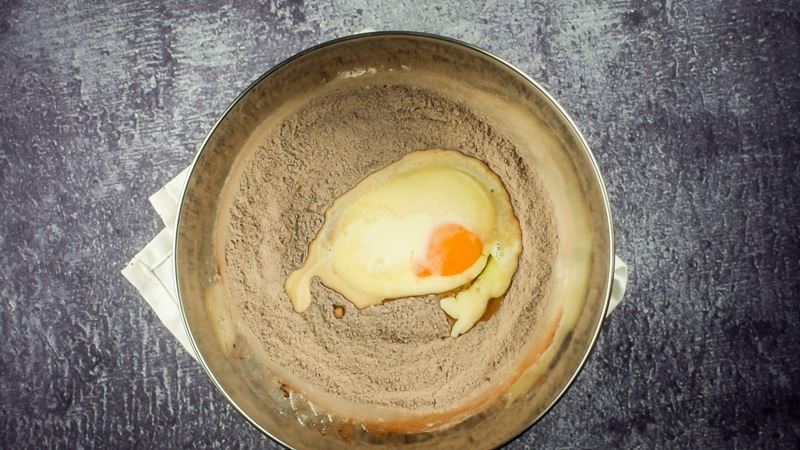 A bowl filled with donut mix, egg and milk.
