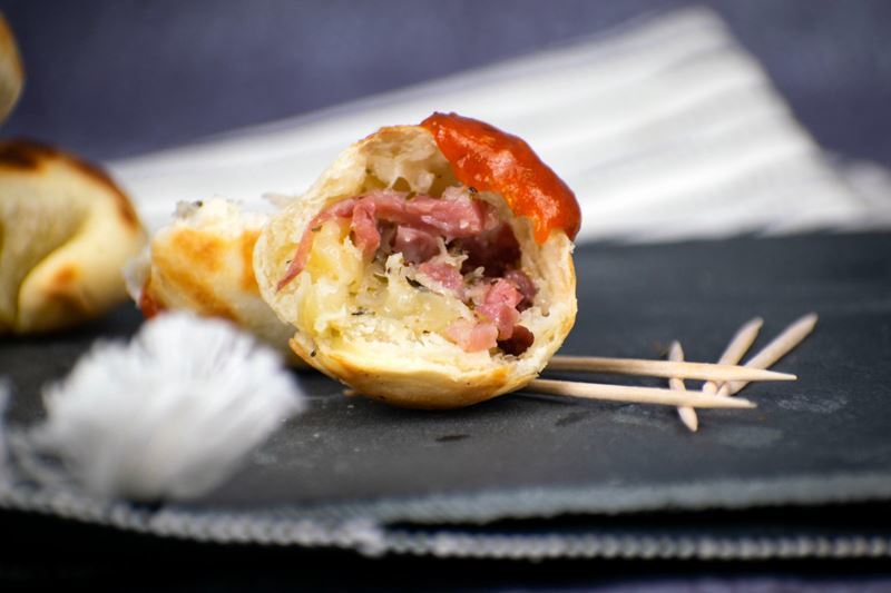 Pizza ball cut in half with tomato sauce on top, toothpicks on the side.