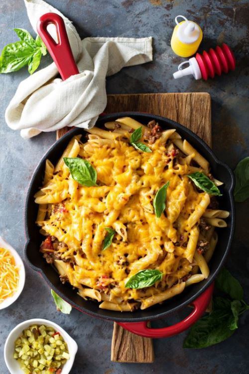 Skillet Penne Pasta with Cheese in skillet on top of a wooden platter.