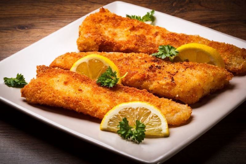 Crispy Fried Fish with Cornmeal and lemon slices on a plate.