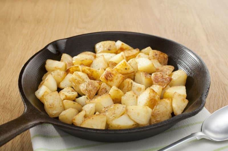 Home Fried Potatoes in a skillet, wood background.