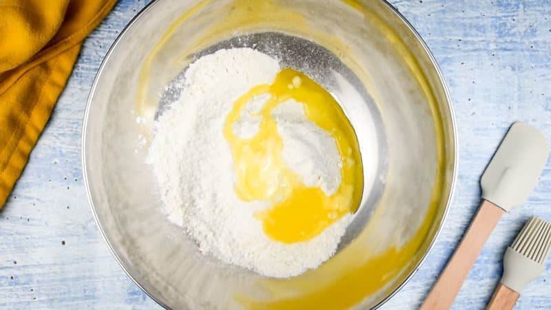 Cake mix and butter in a bowl, spatula and pastry brush on the side.