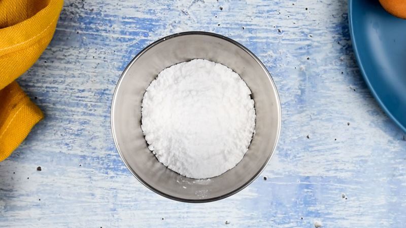 Bowl of powdered sugar on blue background.