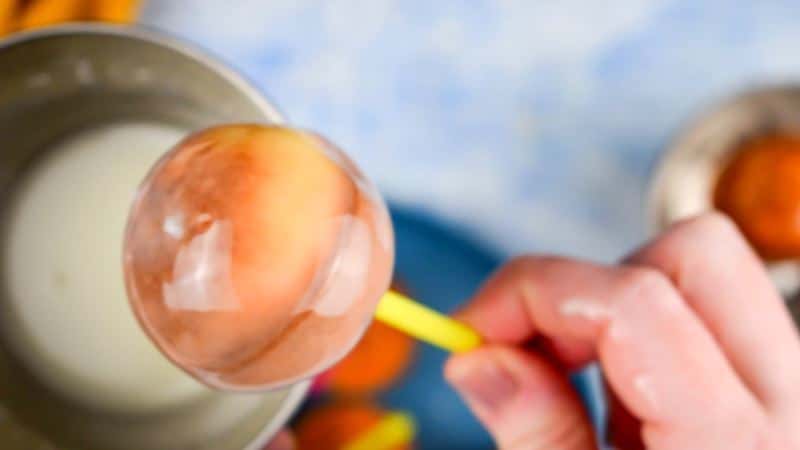 Hand holding a cake pop that has been dipped into sugar coating.