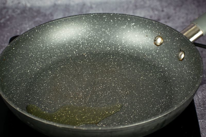 A pan with oil in it heating on an element.