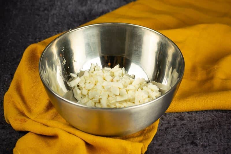 How to Make Pierogies Step 4 Cheese chunks in a bowl, yellow dish cloth underneath.