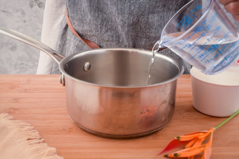 How to Make Simple Syrup Step 2 Water pouring into a pot on the counter.