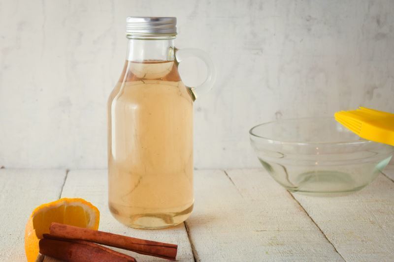 How to Make Simple Syrup Step 5 - Variation 1 A glass bottle of simple syrup, cinnamon and orange on the side.