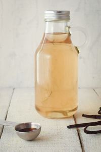 A glass bottle of simple syrup, vanilla beans on the side.