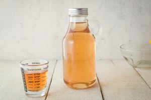 A glass bottle of simple syrup, a small measuring glass on the side.
