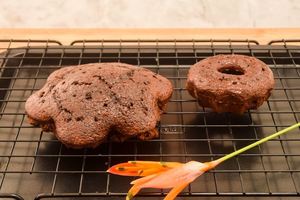 2 chocolate cakes on a cooling rack, with an orange flower.