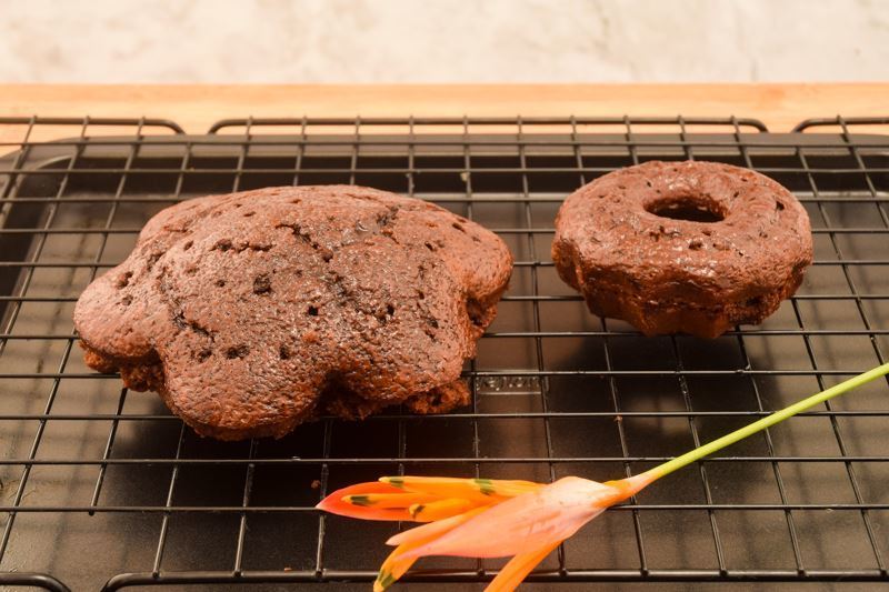 2 chocolate cakes on a cooling rack, with an orange flower.