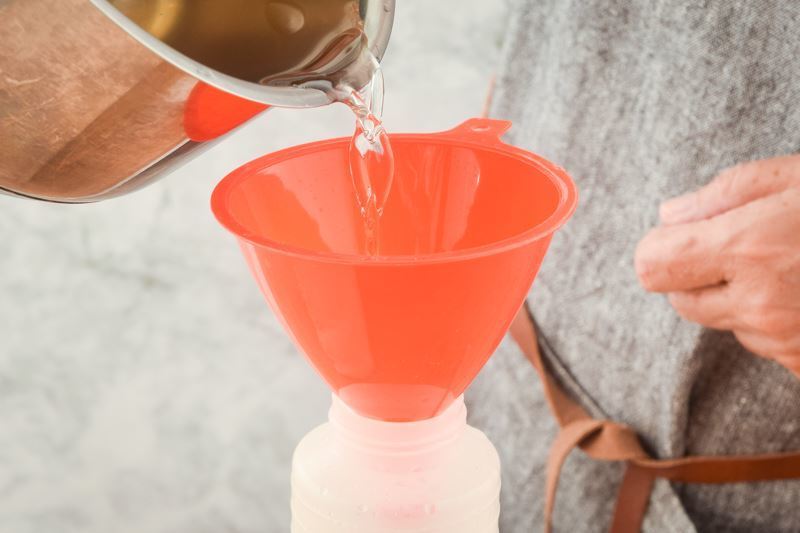 Simply syrup pouring through a funnel into a squeeze bottle.