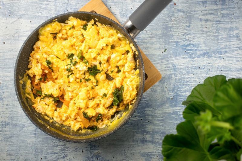 A pot of scrambled eggs with kimchi and kale on counter.