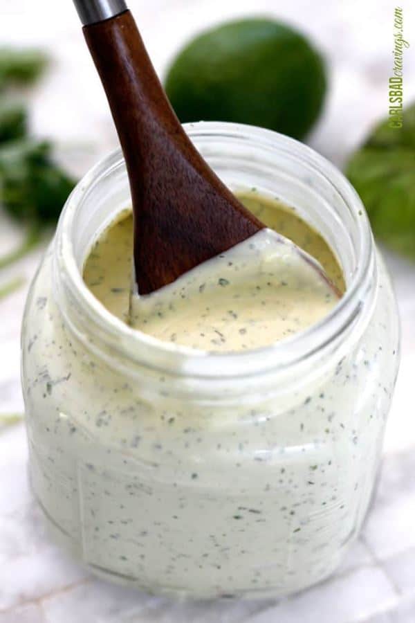 Blender Tomatillo Avocado Ranch Dressing in a small jar with a wooden spoon.