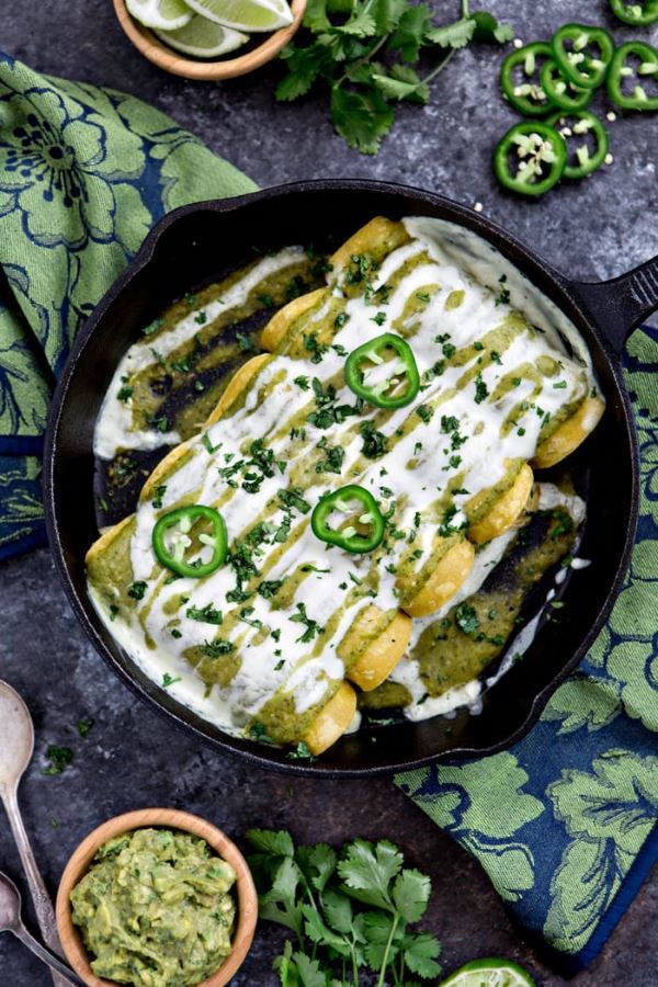 Chicken Black Bean & Spanish Enchiladas with Tomatillo enchilada sauce in a cast iron pan.