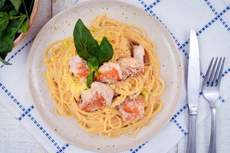 Electric Skillet Spaghetti chicken alfredo on a white speckled plate, garnished with basil leaves.