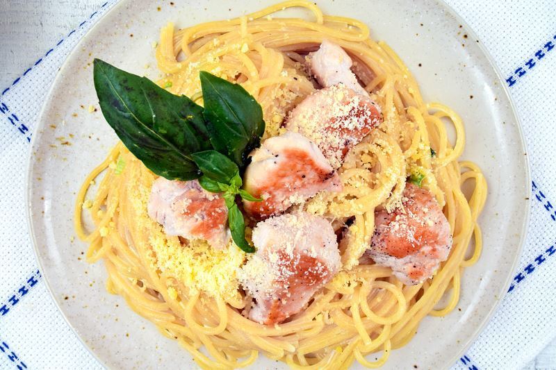 Electric Skillet Spaghetti chicken alfredo on a white speckled plate, garnished with basil leaves.