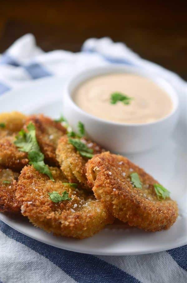 fried green tomatillos on a plate with dipping sauce.