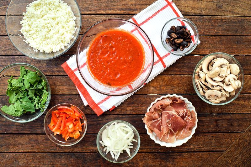How to grill pizza - prepped ingredients on wood background.