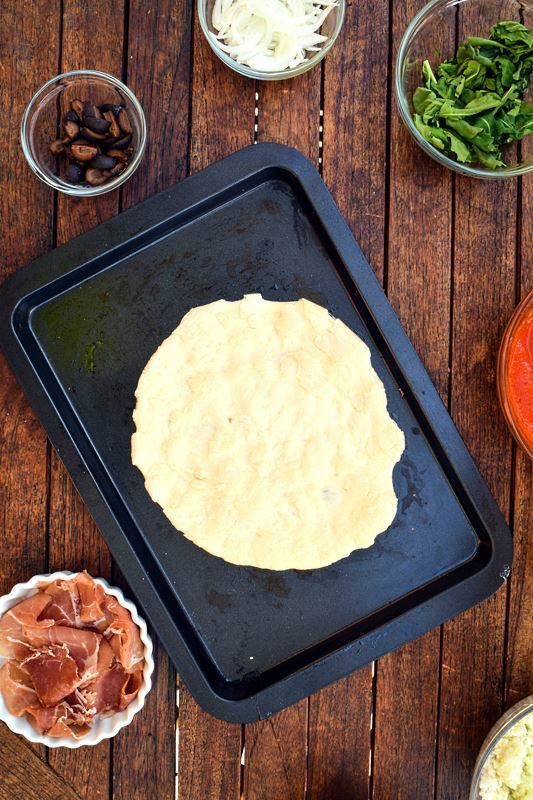 Pizza dough on a pan with toppings.