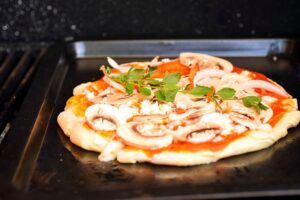Mushroom pizza in a pan on the bbq.