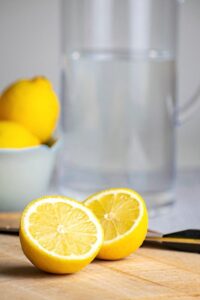 A pitcher of water and a lemon cut in half.