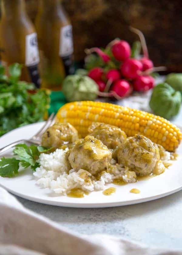 Stuffed Green Chili Meatballs on a plate with corn on the cob and rice.