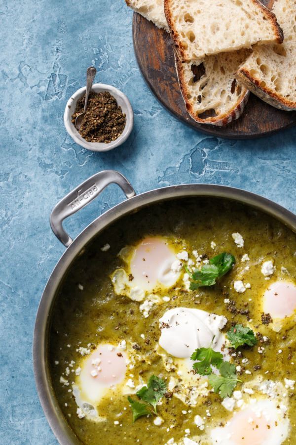 Tomatillo Shakshuka in a pan, on blue background.