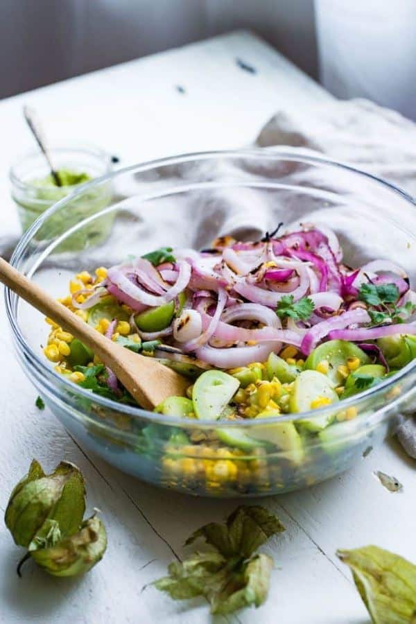 grilled corn salad with tomatillo in a clear glass bowl.