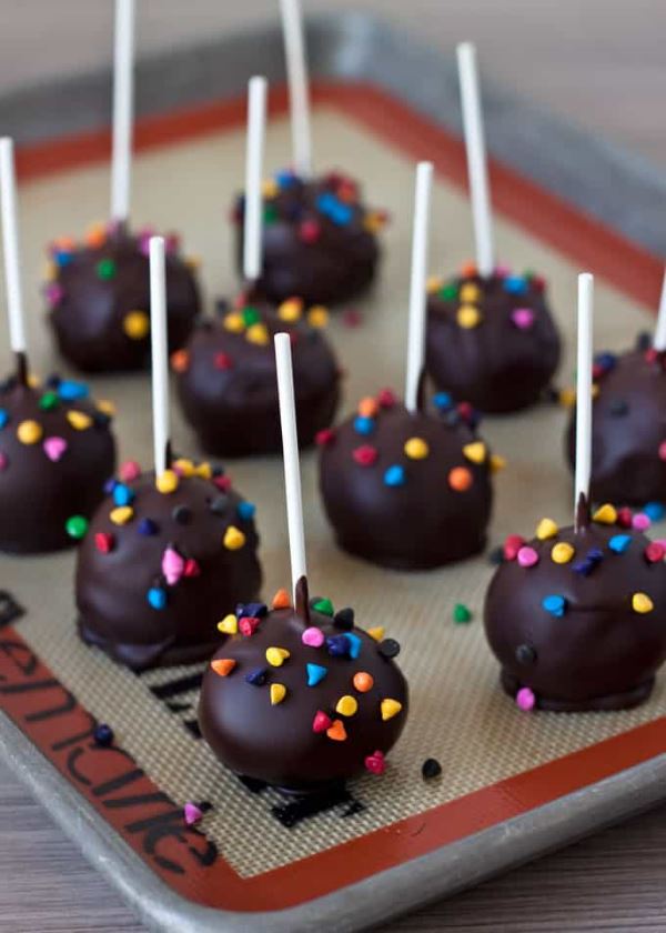Brownie cake pops upside down on a baking tray.