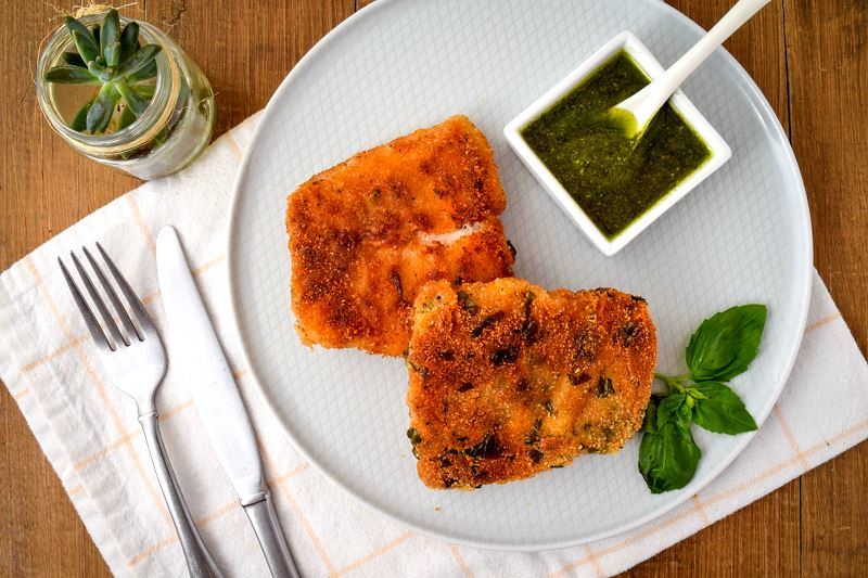 Electric Skillet Fried Fish on a plate with pesto, succulent plant in a jar in the background.