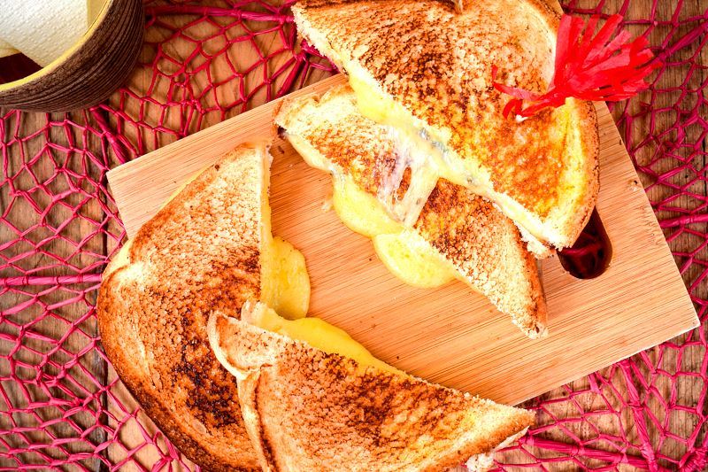 Electric Skillet Grilled Cheese 4 Electric skillet grilled cheese sandwiches on a cutting board. over a pink doiley.