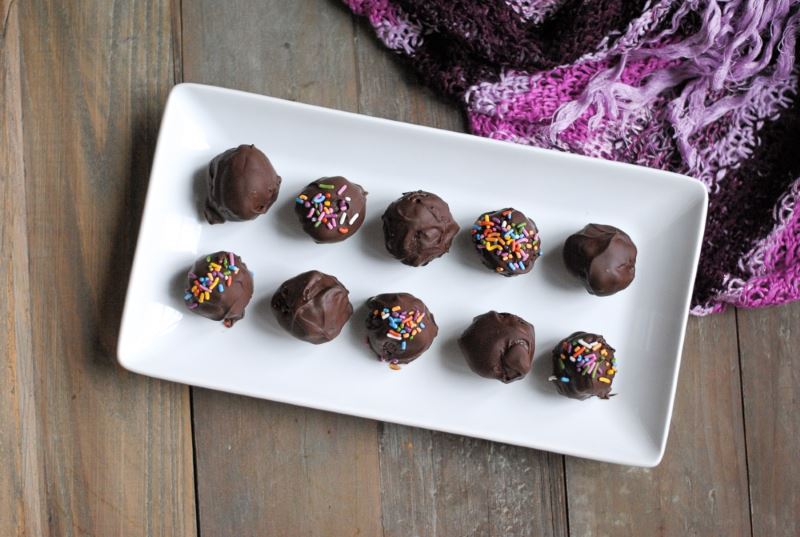 Chocolate gluten free cake balls on a white rectangular dish.