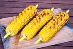 Grilled corn cobs on wooden background.
