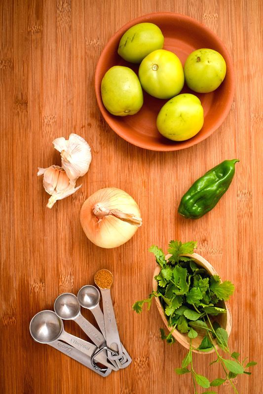 How to Make Tomatillo Salsa_1 A bowl of tomatillos, serrano pepper, garlic, cilantro and spices laid out.